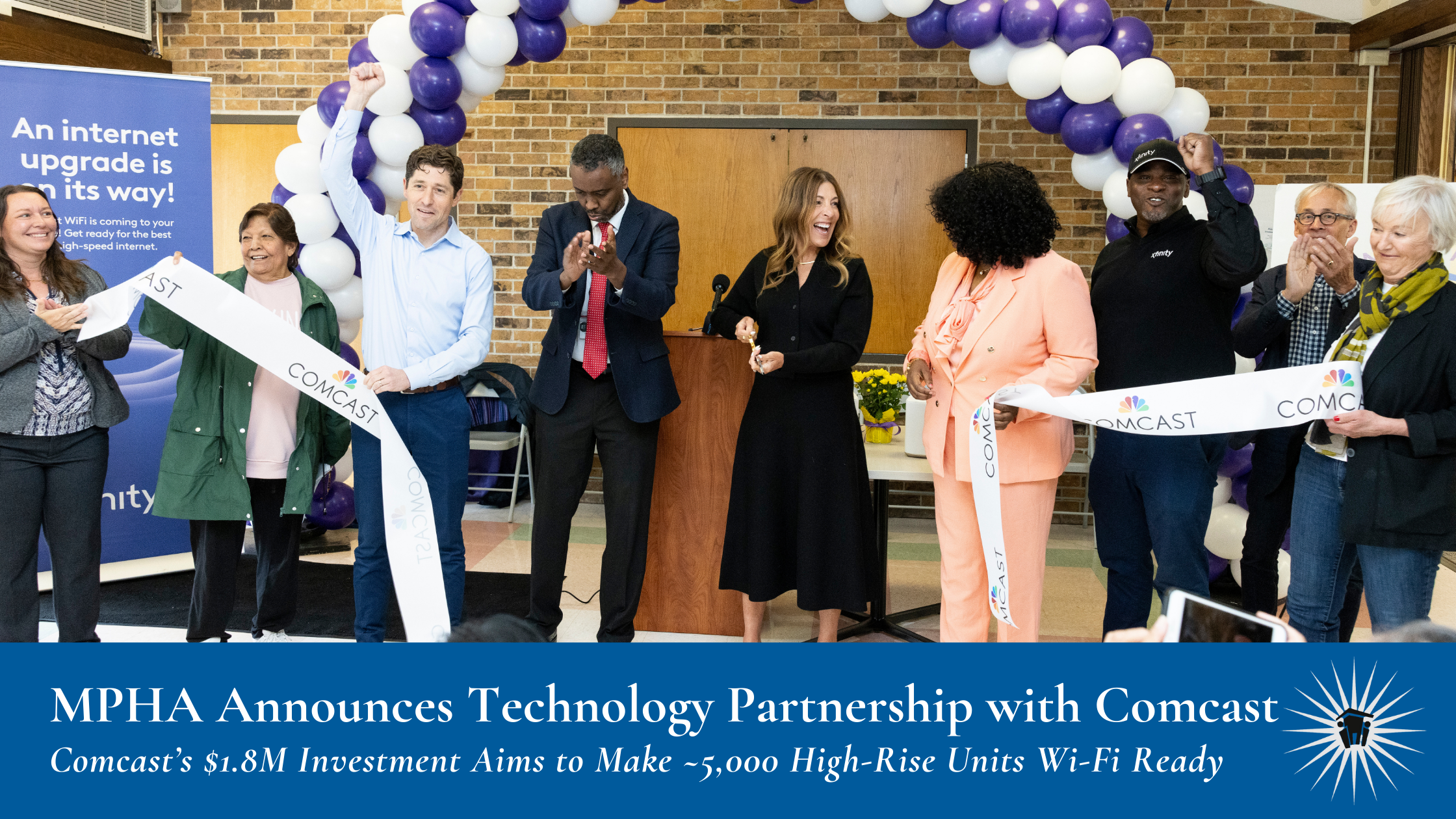 A group of people participates in a ribbon-cutting ceremony indoors, with a purple and white balloon arch in the background.