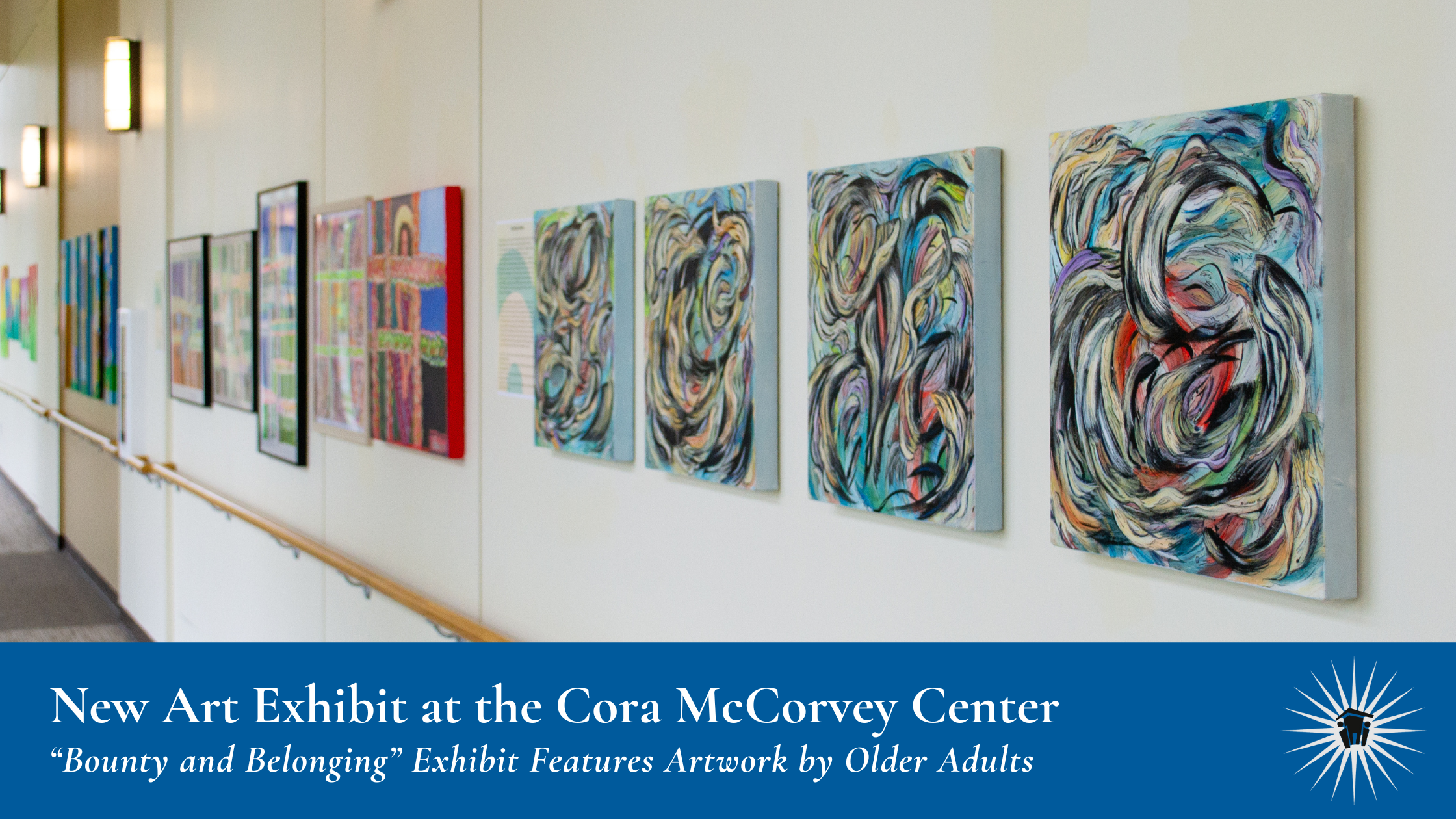 A row of colorful abstract paintings is displayed on a white hallway wall, with handrails and wall-mounted lights visible.