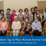 A group of adults pose together indoors at the Korean Service Center.