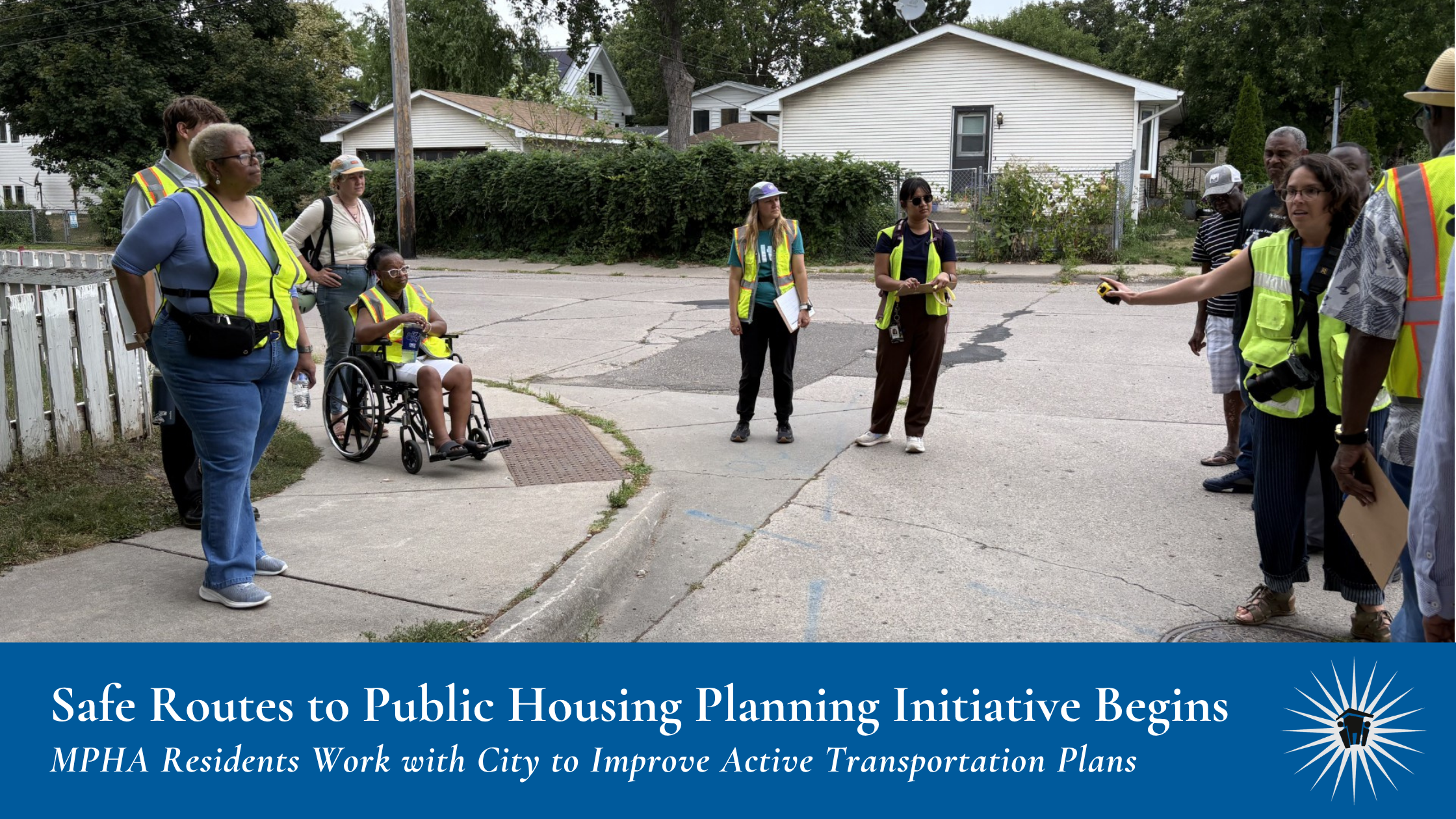 Several individuals in yellow safety vests stand talking in neighborhood walking intersection. Text banner at bottom reads: "Safe Routes to Public Housing Planning Initiative Begins, MPHA Residents Work with City to Improve Active Transportation Plans